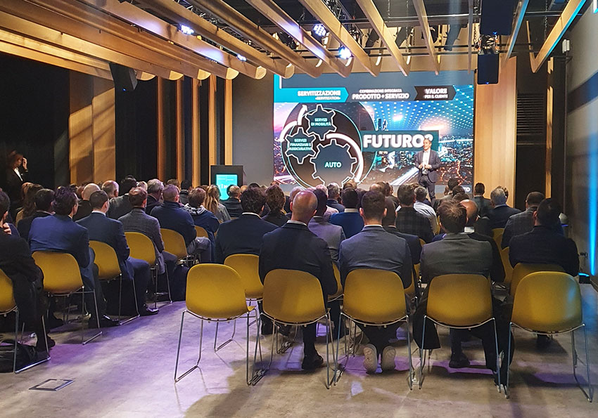 Convention Kinto platea di spalle, relatore parla sul palco, dietro di lui grande schermo per la presentazione