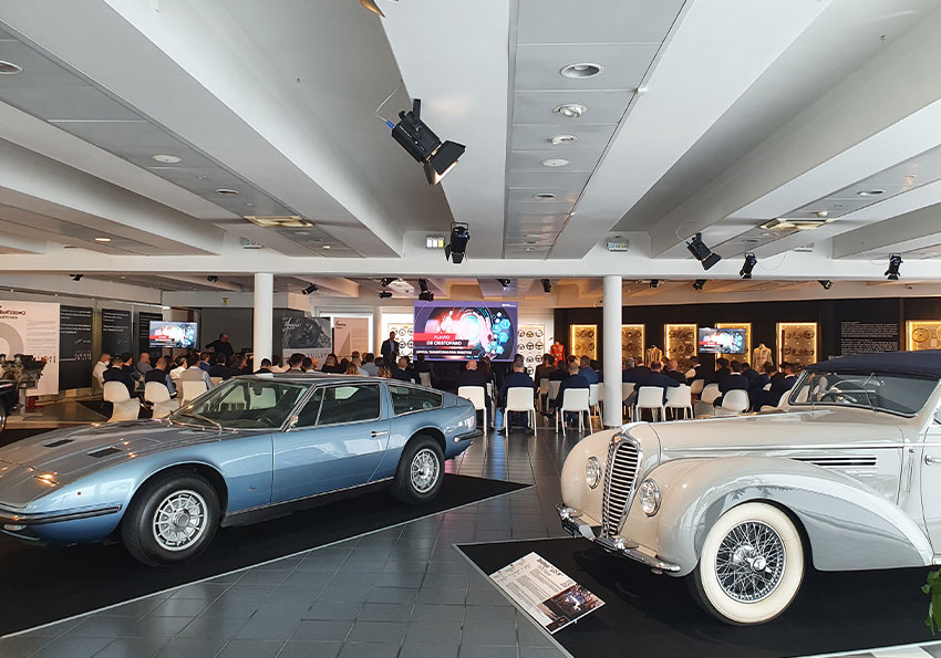Auto d'epoca alla convention Toyota Financial Service, sullo sfondo la platea e lo schermo che proietta la relazione aziendale