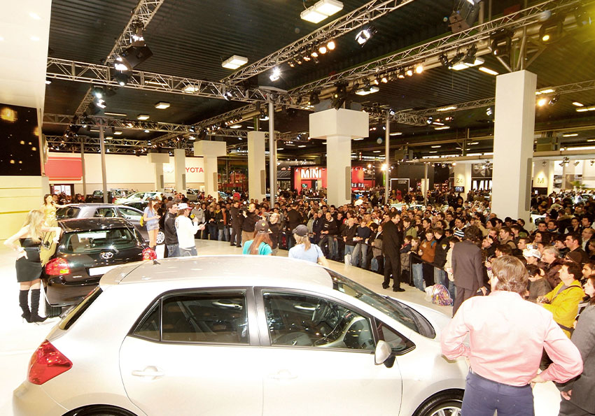 folla osserva le auto in esposizione presso gli stand