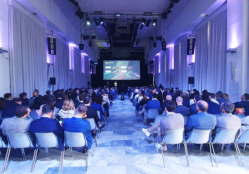 Platea di spettatori che ascoltano il relatore presentare la mission dell'evento aziendale